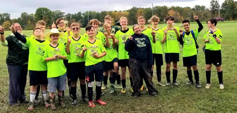 Older Bethel soccer team in yellow with coaches