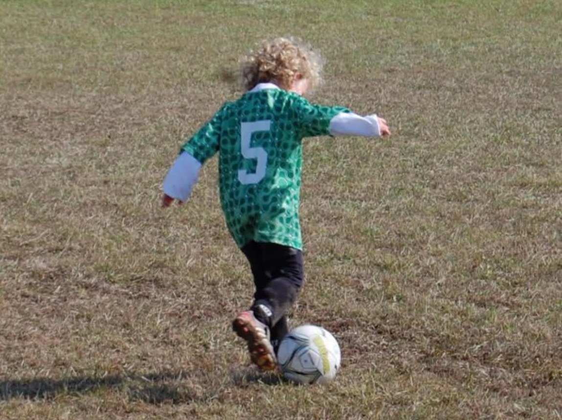 Young Bethel soccer player kicking the ball
